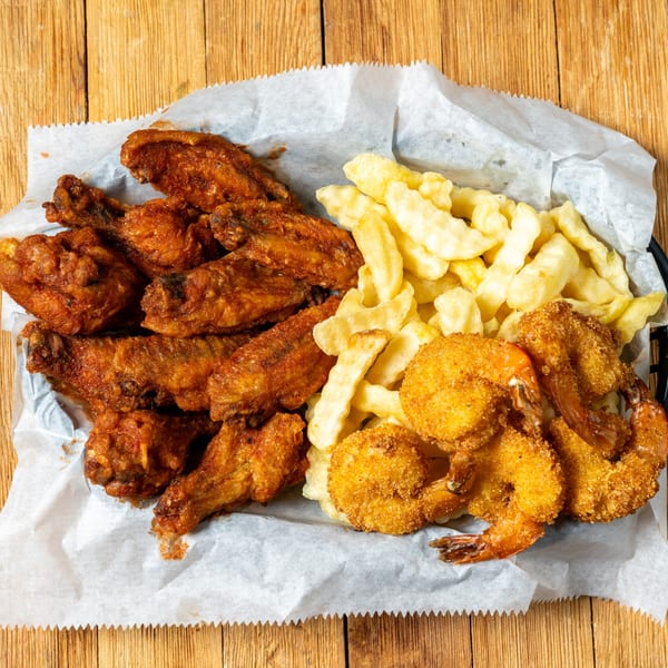 A basket of J.R. Crickets' fried chicken wings, crinkle-cut fries, and breaded shrimp.