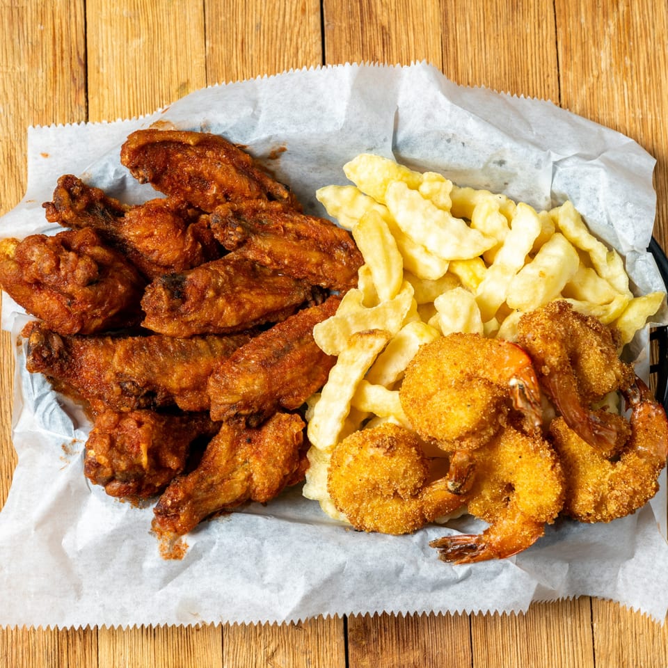 A basket of J.R. Crickets' fried chicken wings, crinkle-cut fries, and breaded shrimp.