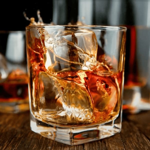 Whiskey with ice cubes splashing in a glass on a wooden table at J.R. Crickets McDonough.
